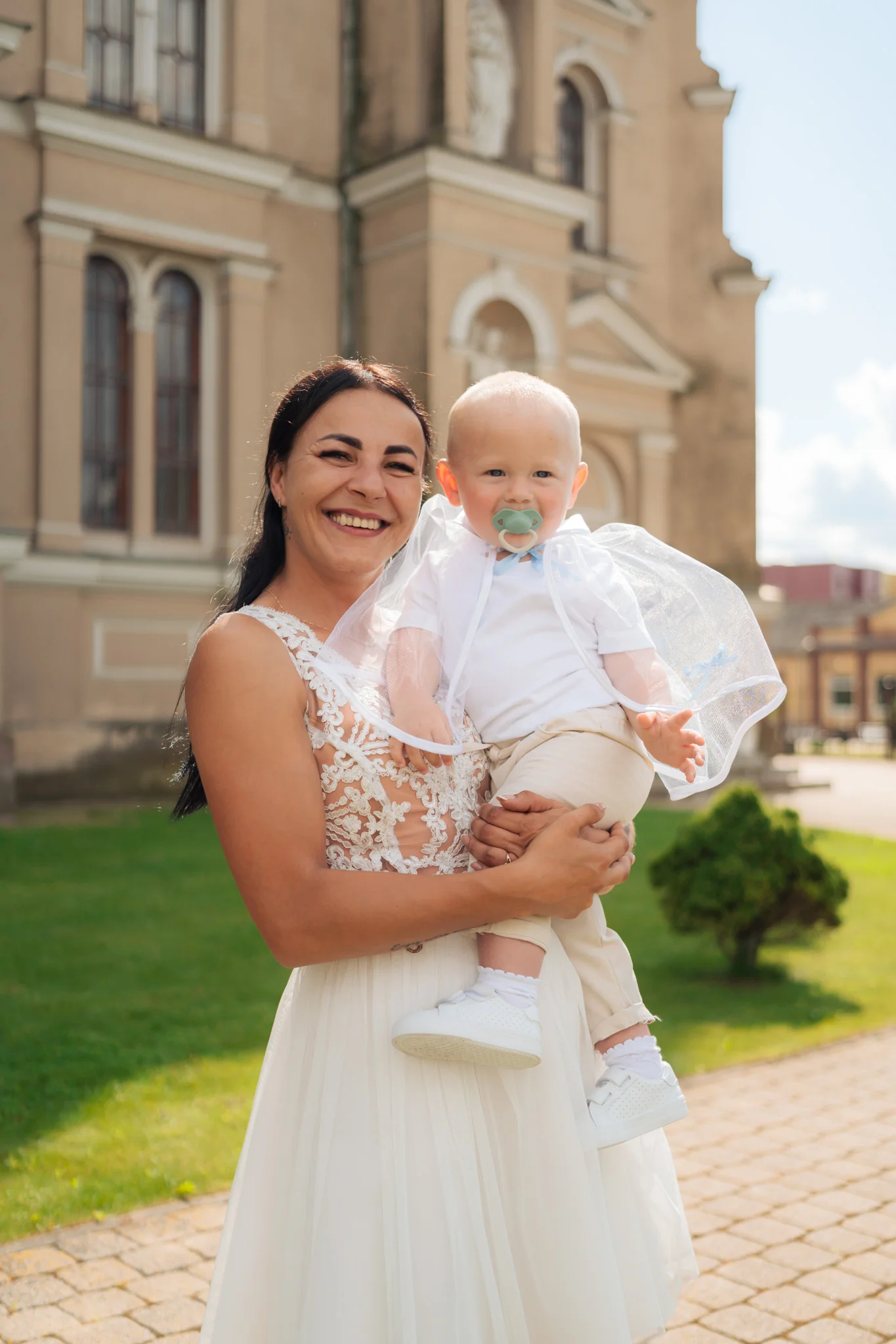 Mama su kūdikiu lauke prie bažnyčios Joniškyje